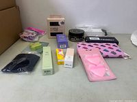 Photo of all lot items arranged showing beauty products, skincare items, heart-shaped makeup sponges, and printed pouch.