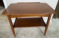 Front view of walnut end table showing top, shelf, and legs
