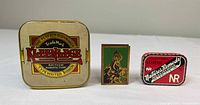 Front view showing Kleeneege typewriter ribbon tin, brass matchbook cover, NR laxative tin