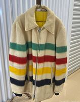 Front view of cream wool coat with multicolour stripes and zip closure