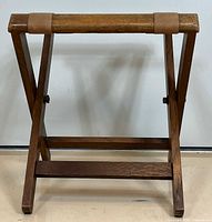 Front view of folded wooden luggage rack with canvas straps