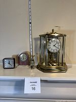 Group shot of four clocks including brass glass anniversary clock, alarm clock, mantel clock, novelty golf bag clock