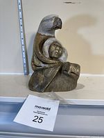 Front view of carved stone sculpture with bird, human face, and animal head