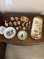 Full lot on tabletop showing all miniature ceramics, plates, tray, shoe figurines and dog