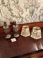 Two glass lamp bases and two hexagonal floral shades displayed on wood surface