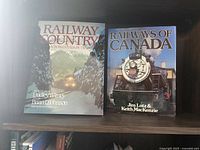 Two large railroad themed books titled 'Railway Country' and 'Railways of Canada' shown with photographic covers featuring a train and railroad scenes.