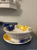 Photo of ceramic bowl placed on matching ceramic plate, showing the blue and yellow floral design on white background.