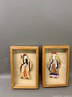 Two framed Chinese silk figures, warrior and elder, with glass front wooden frames, shown side by side