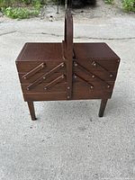 Closed view of the expandable wooden sewing box showing exterior and carrying handle.