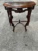 Full view of the French Baroque-style carved figures end table on concrete surface.