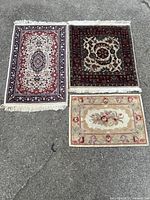 Overview photo of all three hand-woven mats laid out on pavement showing sizes, designs, and fringed edges on two