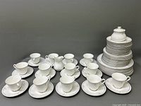 Overview of entire China set stacked and arranged showing cups, plates, creamer, and sugar bowl