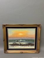 Frontal photo showing the full painting of the seascape including the boat and waves, framed in an ornate gold wooden frame with blue inner border.