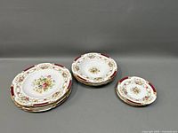 Three stacks of Shelley Dubarry Ware plates: salad plates, soup plates, and bread plates arranged with visible floral and burgundy gold trim design.