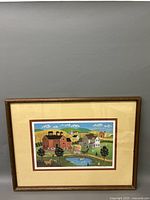Framed lithograph showing a colorful rural scene with buildings, trees, pond, and people on a path.