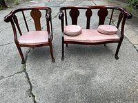 Photo showing full view of the armchair and settee placed side by side outdoors on concrete, highlighting their wooden frames and upholstered seats.