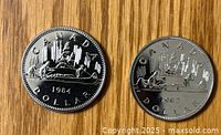 Obverse and reverse views of two Canadian silver dollars, 1983 and 1984, showing the Voyageur canoe design and Queen Elizabeth II's profile.