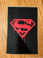 Front of sealed Superman Memorial Set with red dripping Superman symbol on a black background.