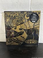 Front of the vinyl record showing psychedelic design art with band and album name in gold and black.