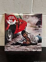 Front cover of the vinyl album depicting a scene from the movie with a man holding a gun next to a red car.