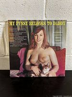 Front cover of 'My Pussy Belongs To Daddy' vinyl record showing illustrated topless woman holding a cat, with song titles visible.