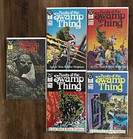 Five comic books from the series Roots of the Swamp Thing arranged on a wooden floor, showing the cover artwork for each issue - parts 1 to 5.