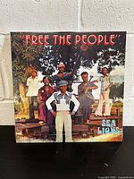 Front cover of Sea Lions "Free The People" vinyl record showing the band members posing outdoors with a large artillery gun.