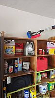 Wide shelf view of automotive supplies including oils, washer fluid, gas can, spray cans and bottles