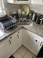 Overview of kitchen counter corner showing multiple items including dish rack, tea set, jugs and kettle