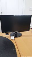 Samsung widescreen monitor with circular base on desk.
