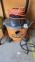 Ridgid 34.1 litre orange and black shop vacuum with orange extension cord wrapped on top