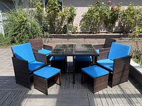 Full set of table, chairs and foot rests on a wooden deck under sunlight