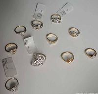 Overview photo showing all 10 gold-tone jewellers display sample rings with different simulated diamond designs and display tags attached.