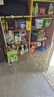 Image of wooden shelves with multiple bottles and containers of garden care products including fertilizers, sprays, and treatments