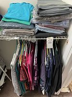 Wide view of men’s and women’s tops on hangers and folded stacks on shelf