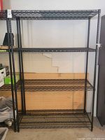 Front view of the black metal wire shelving rack with four shelves, showing overall size and shelf spacing.