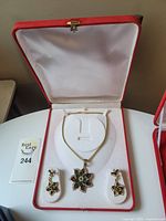 Necklace and matching earrings displayed in the open red jewelry box with white lining.