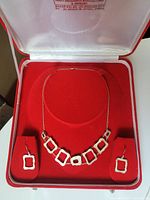 Sterling silver necklace and earrings set with square open-link design, inside a red velvet box with white satin lining and Mohinder branding on the lid.