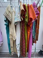 Photo showing nine traditional Indian dresses on hangers in various colors with embroidery and embellishments.