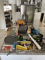 Wide shot of kitchen countertop with toaster oven, folding tables, kitchen scales, and various culinary tools.