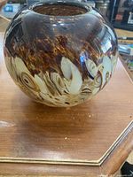 Side view of the round glass vase showing the mottled brown and white pattern.
