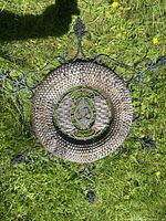 View of the full cast-iron wall hanging with detailed lattice and frame design on grass surface.
