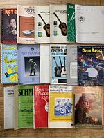 Box of assorted music method and instruction books for guitar, piano, harmonica, and drum basics.
