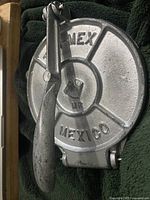 Closed view of cast iron taco maker press showing embossed 'MEXICO' text and handle.