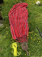 Full view of the red striped fabric hammock laid out on grass showing length and pattern.