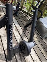 Side-angle view of Schwinn bike trainer black metal frame showing branding and resistance unit knob.