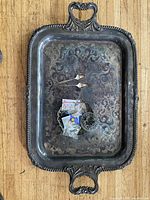 Top view of tarnished silver plated tray with spoons dish and pins placed in center