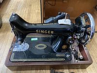 Singer black metal sewing machine model 99K with gold Sapphire decals and lettering, placed on a wooden table.