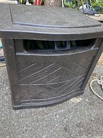 Closed black Suncast hose reel container showing front textured design and integrated handle slot.