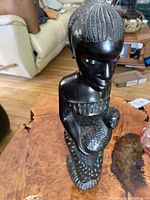 Front view of hand-carved wooden sculpture showing woman's face and child in arms.